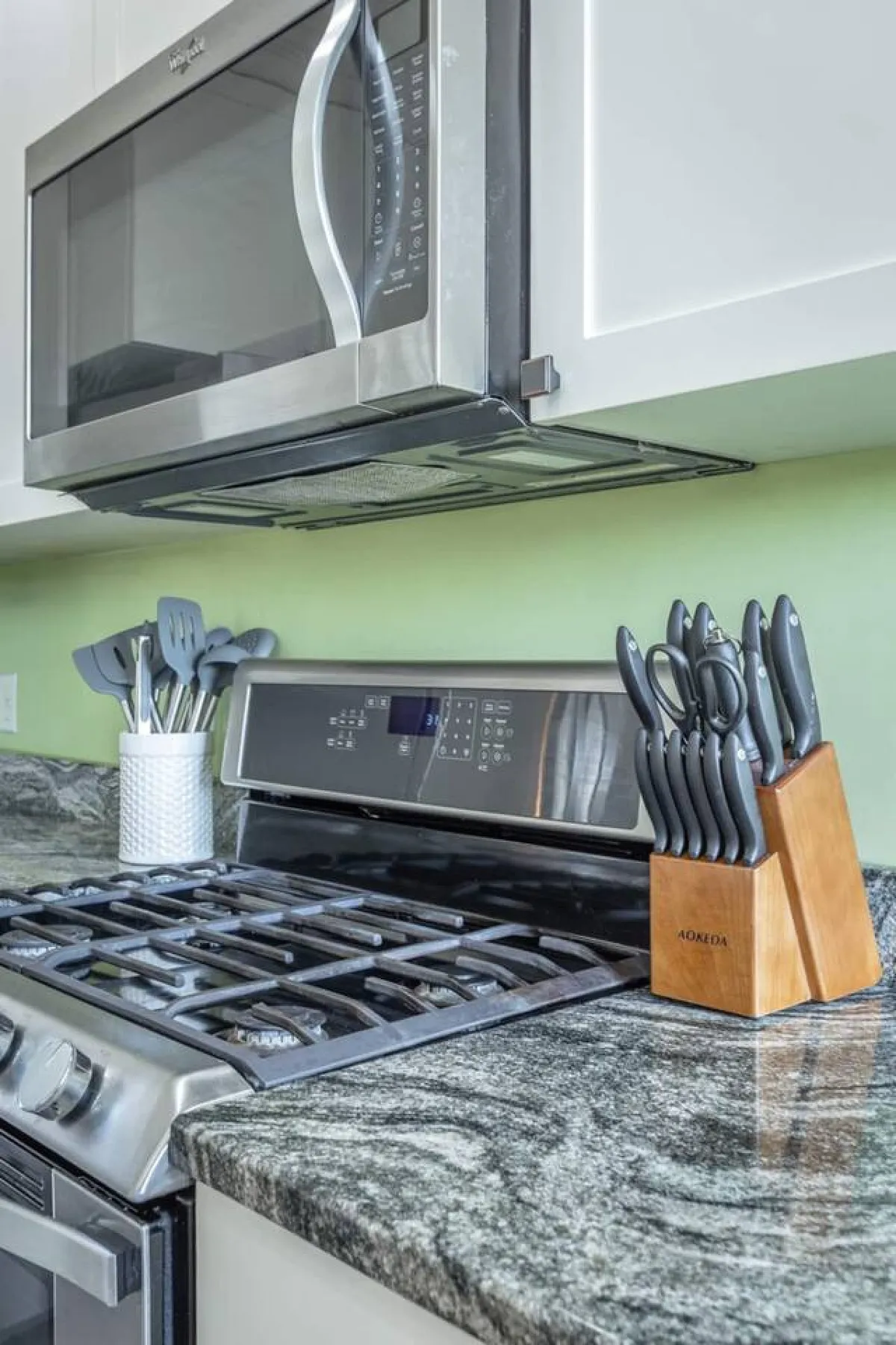 A close-up view of essential kitchen tools and appliances, including a microwave, gas stove, knife block, and utensil holder. The space looks practical and ready for cooking up anything from quick snacks to elaborate family dinners.