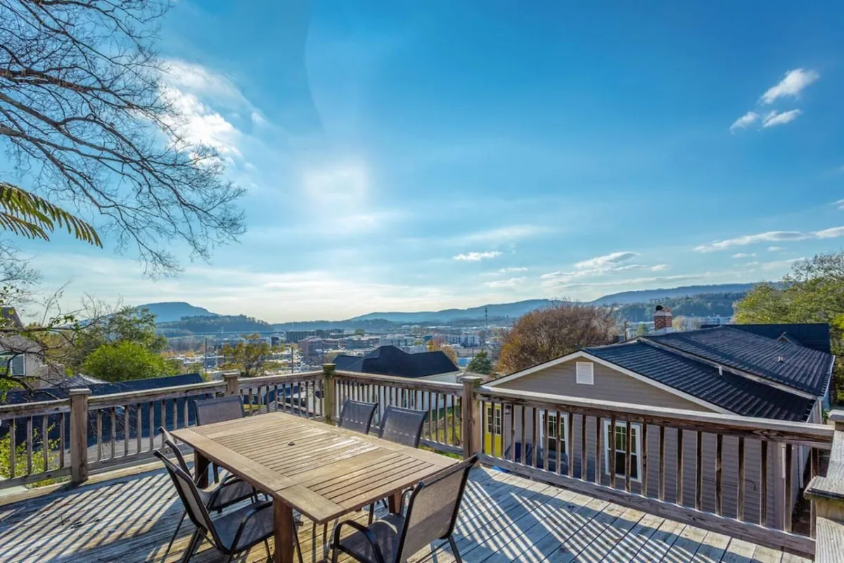 A wooden outdoor dining table and chairs positioned to overlook a panoramic city and mountain view. The setup is casual yet inviting, making it ideal for morning coffee or evening gatherings while taking in the scenery.