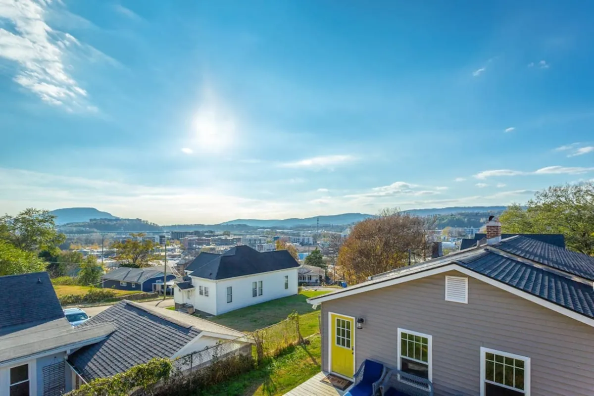 A scenic view of distant mountains and the town below, set against a blue sky. This tranquil outlook evokes a sense of place and the unique atmosphere Chattanooga offers after dark, from sunset to stargazing.